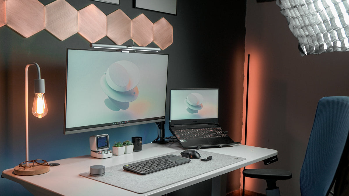 White desk with a monitor light bar and laptop under wood hexagon wall lights