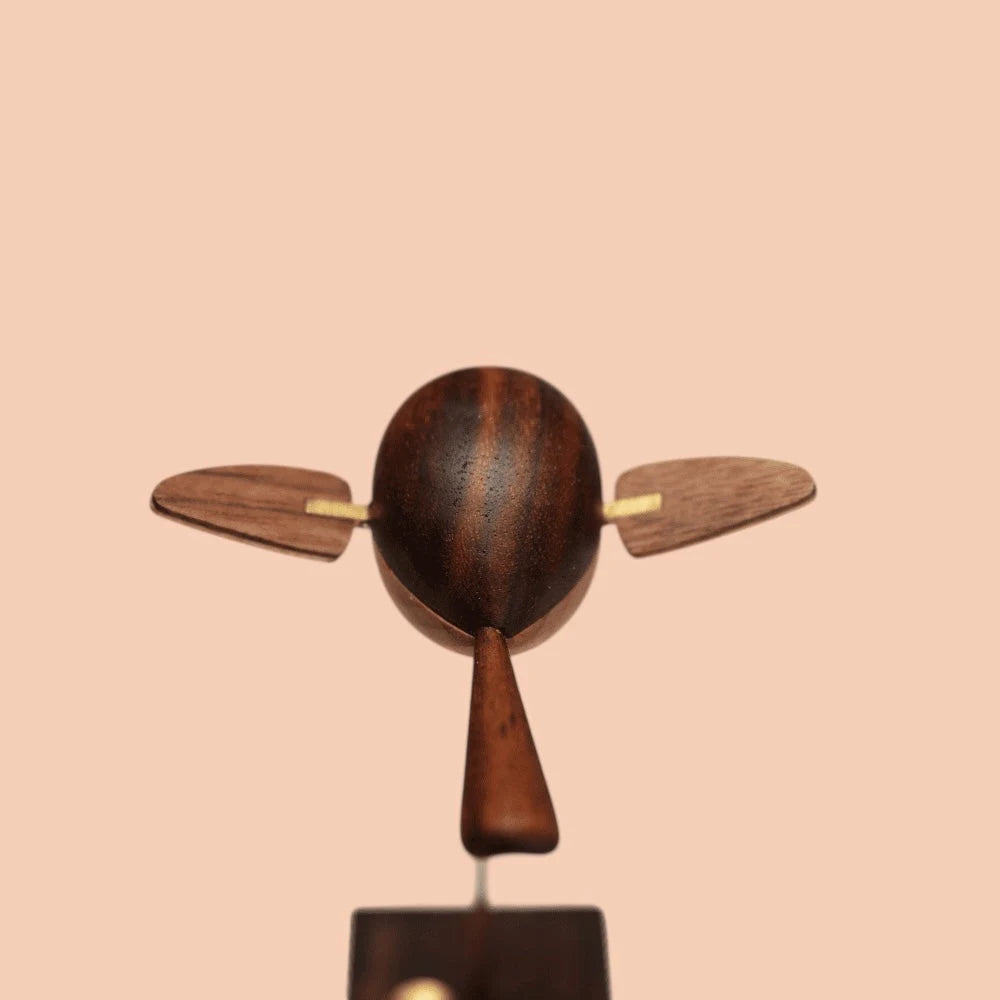 The bird from behind: a striped dark wood body, a pointed tail and two wings spread wide.