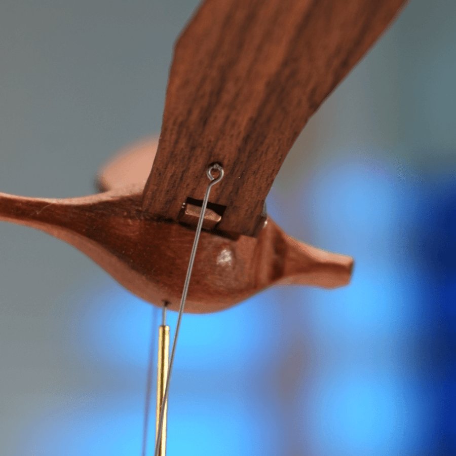 Where the thin wire meets the underside of the swan body, a brass rod below.