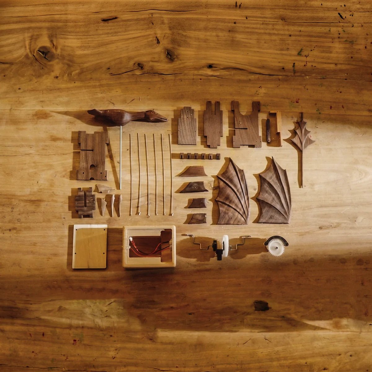 Every part of the Wyvernwood dragon laid out on a wooden table: wings, body segments, wires, the tower and its base
