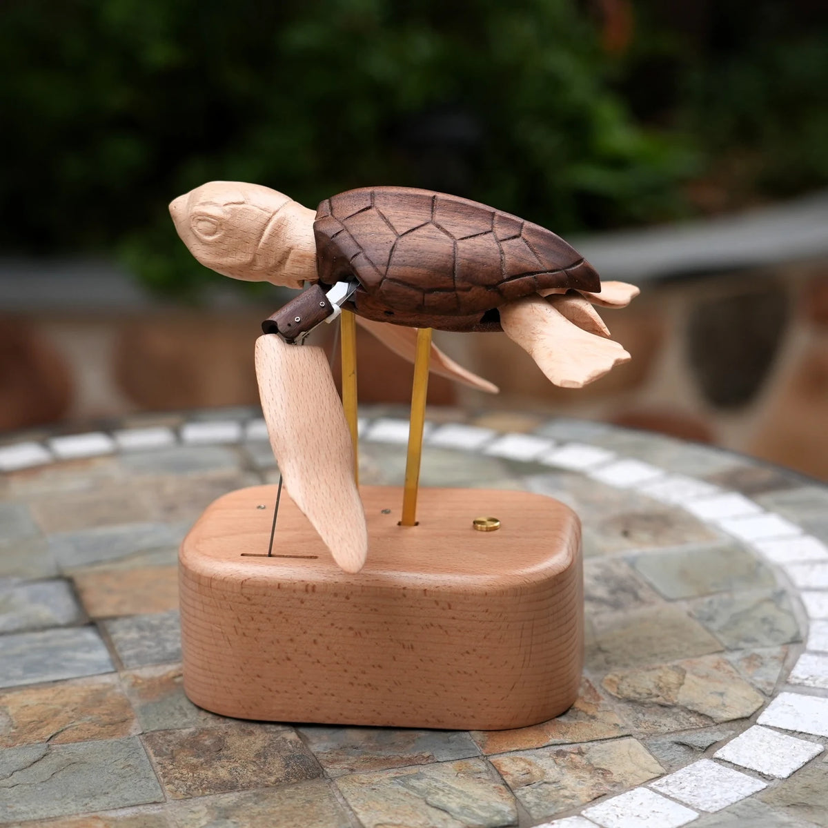 Sea turtle automaton on an oval base on a stone-topped garden table.