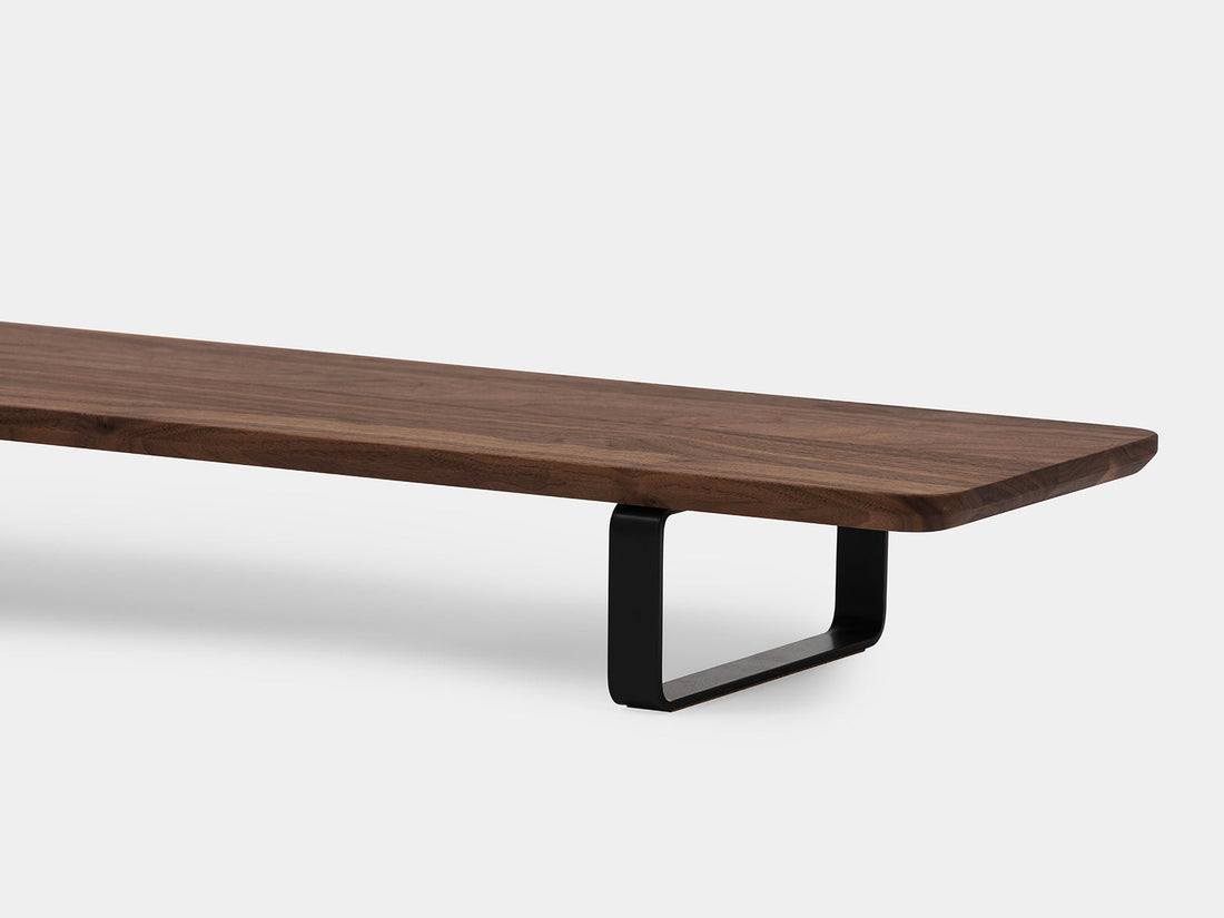 Close-up of the walnut shelf edge and a black U-shaped leg