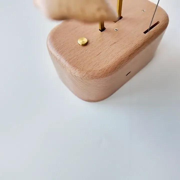 Corner of the oval wood base with two brass rods rising and a small brass button.