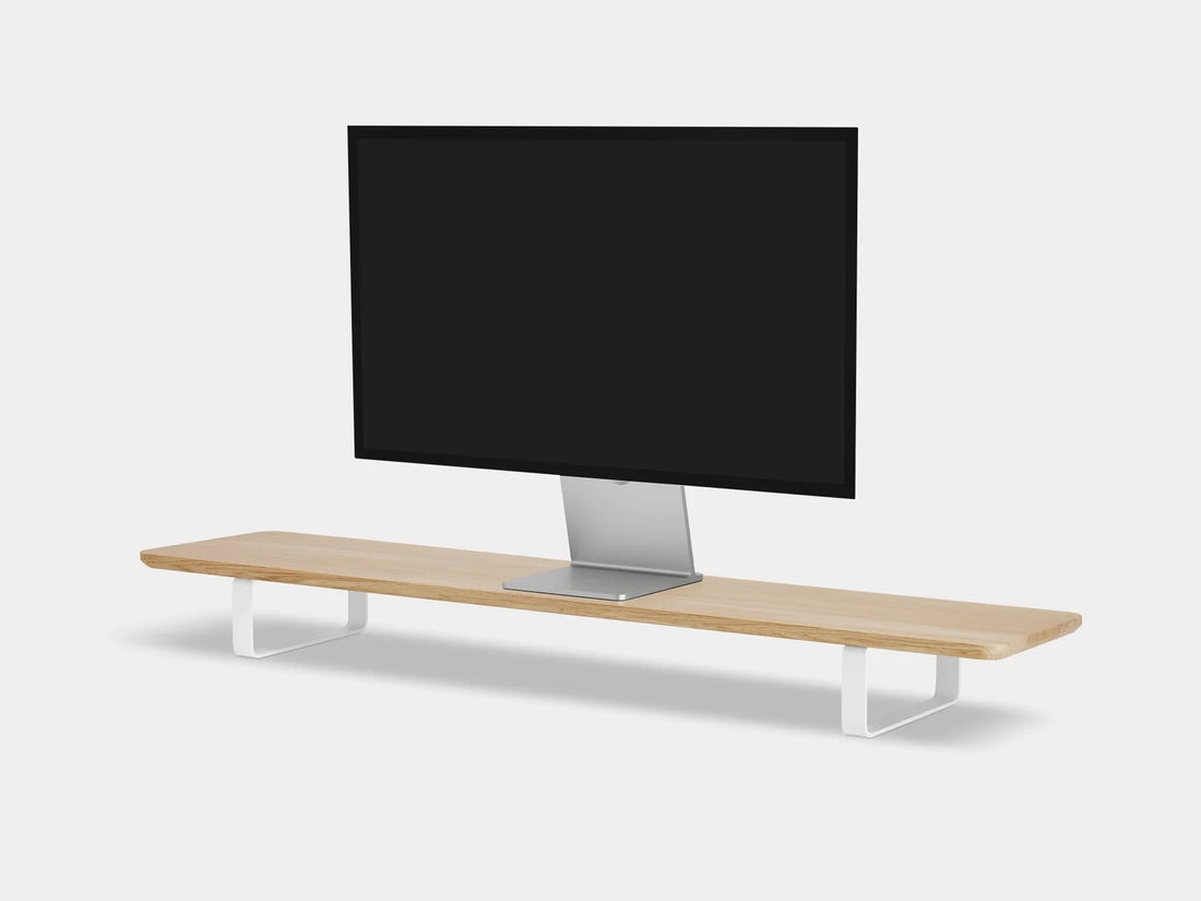 Light oak desk shelf with white legs under a monitor, three-quarter view