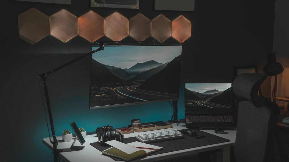 Dark room desk with a mountain wallpaper monitor and hexagon wall lights