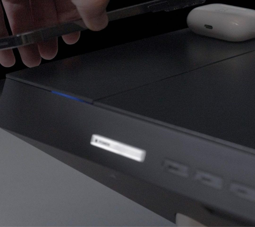 Hand placing an accessory on a black desk shelf with built-in ports