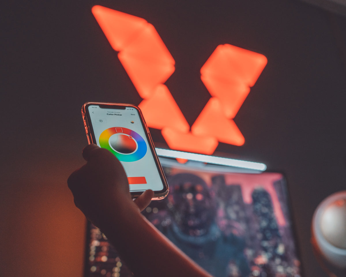 Hand holding a phone with a color picker app in front of orange light panels