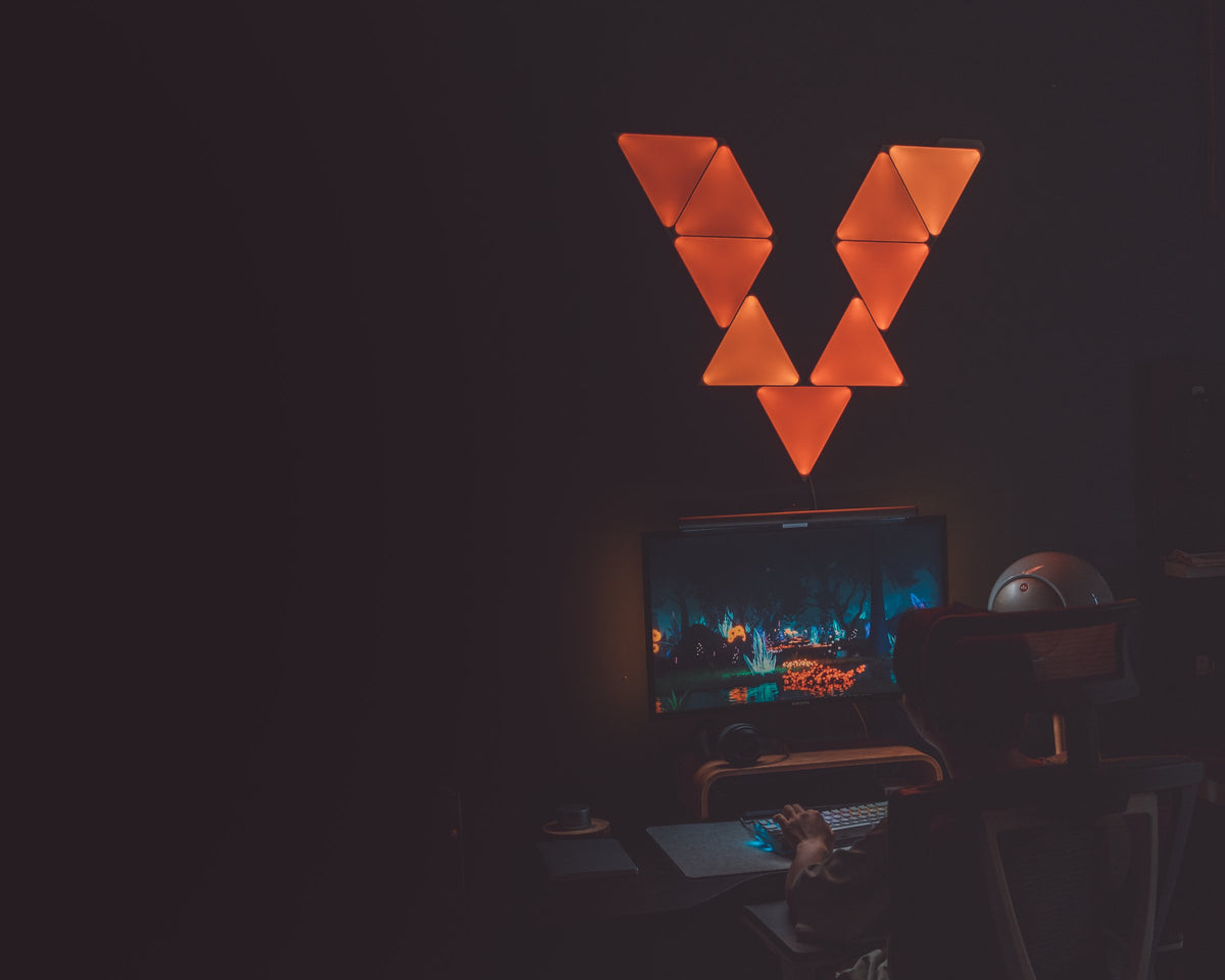 Orange triangle light panels glowing above a dark desk setup