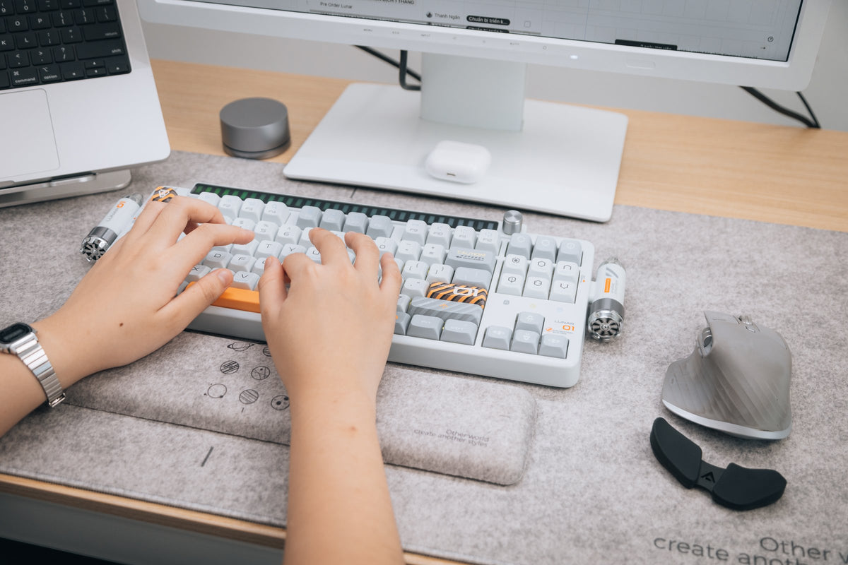 Hands typing on a retro-style mechanical keyboard on a gray felt desk mat