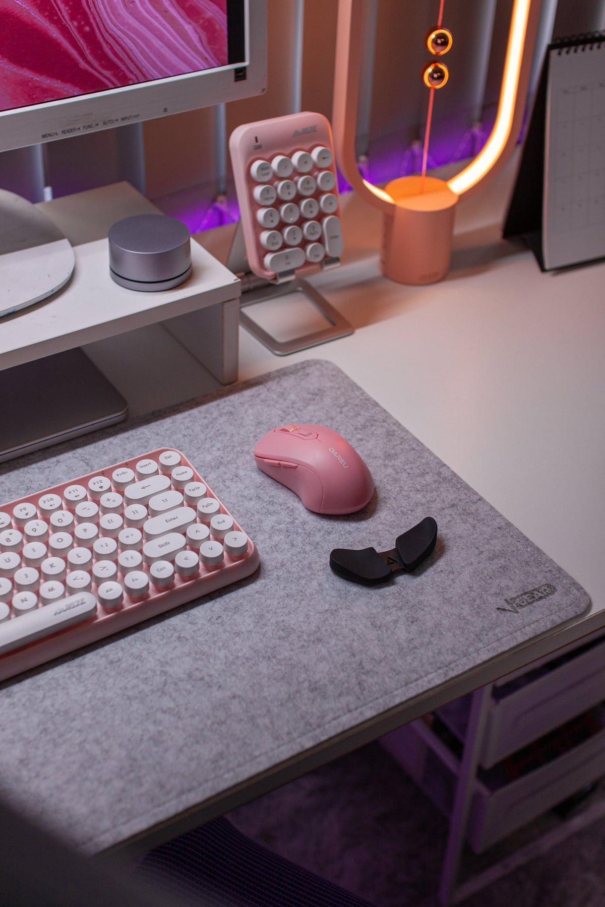 Pink keyboard, numpad and balance lamp on a white desk with purple underglow
