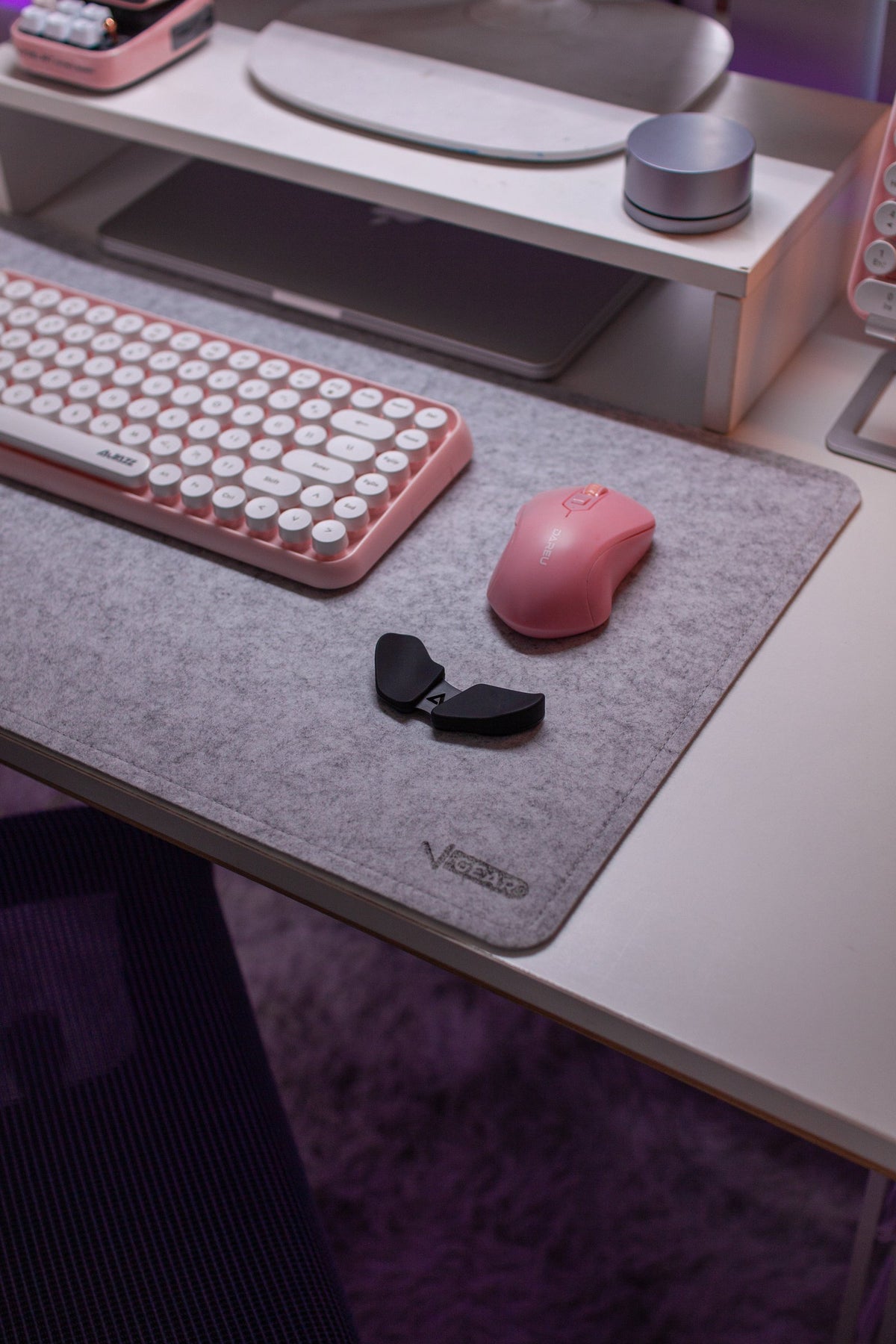 Pink round-key keyboard and pink mouse on a gray felt desk mat