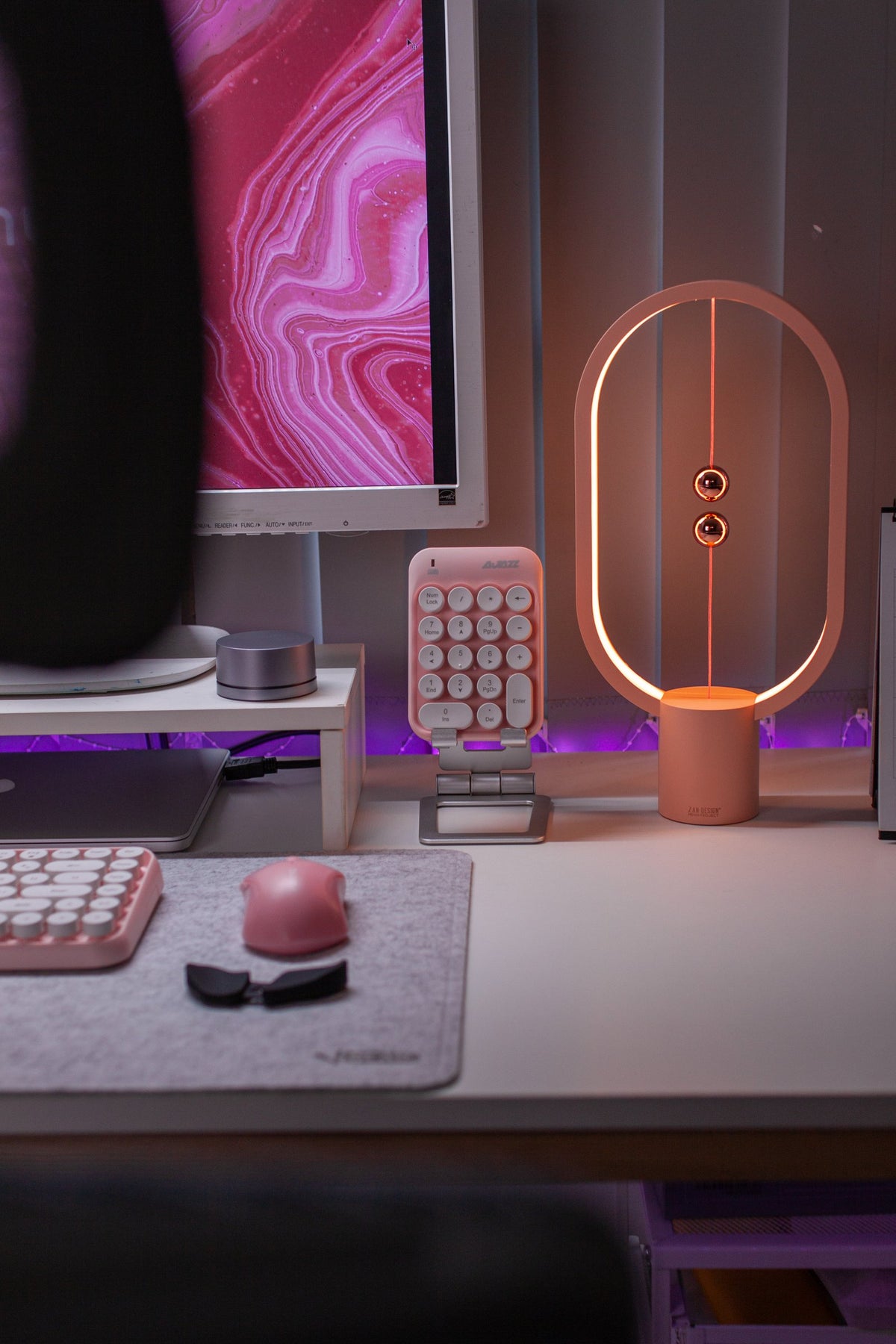 Balance lamp and pink accessories on a white desk under a pink marble screen