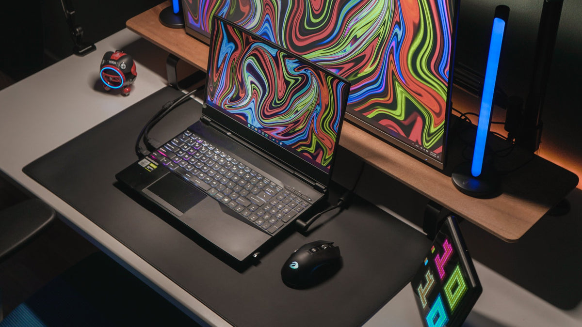 Gaming laptop and monitor with colorful wallpaper between RGB light bars