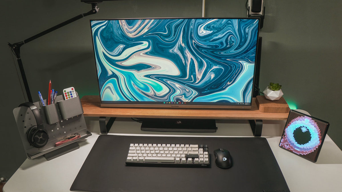 Dark desk with a blue marble wallpaper monitor, pegboard organizer and pixel display