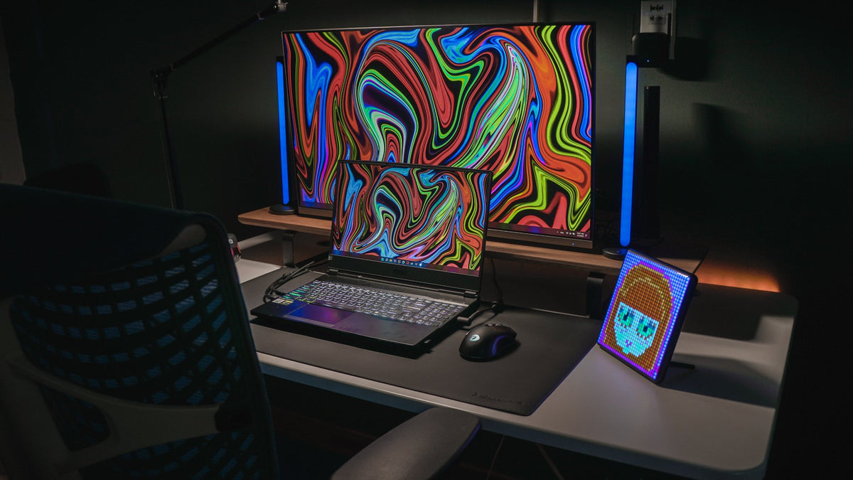 Dark desk with psychedelic wallpaper screens, RGB light bars and a pixel display