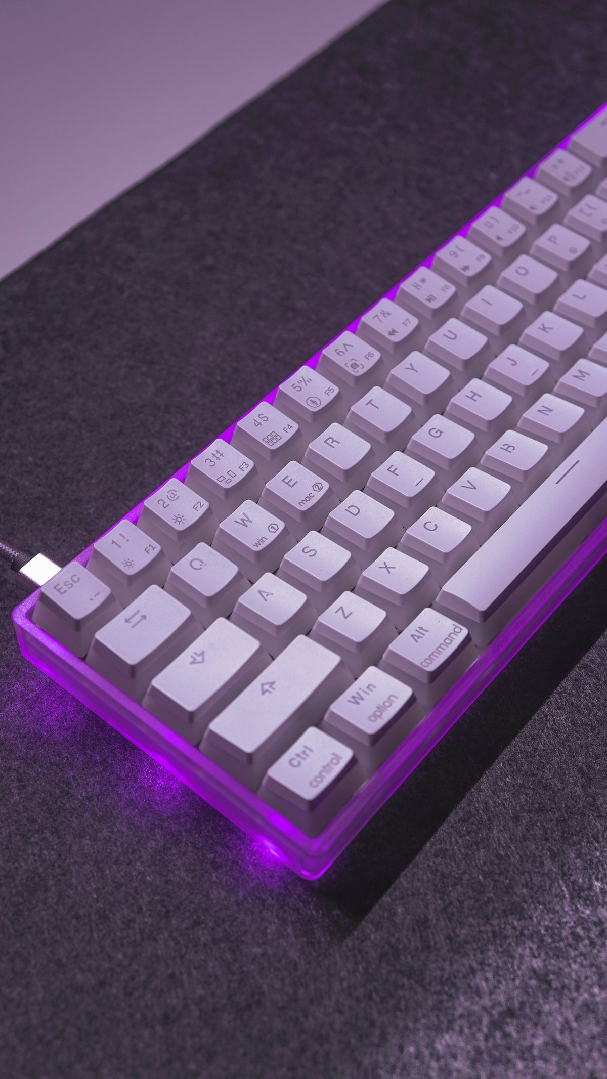 White low-profile keyboard with purple underglow on a dark desk mat