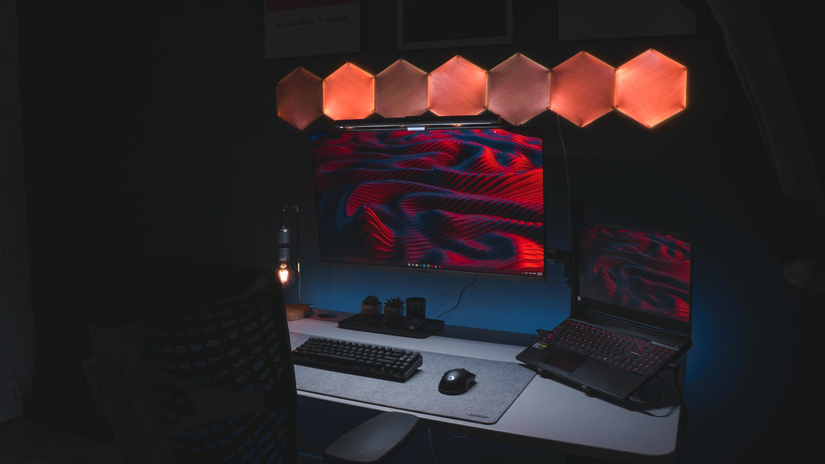 Dark room desk with red wave screens under glowing wood hexagon lights