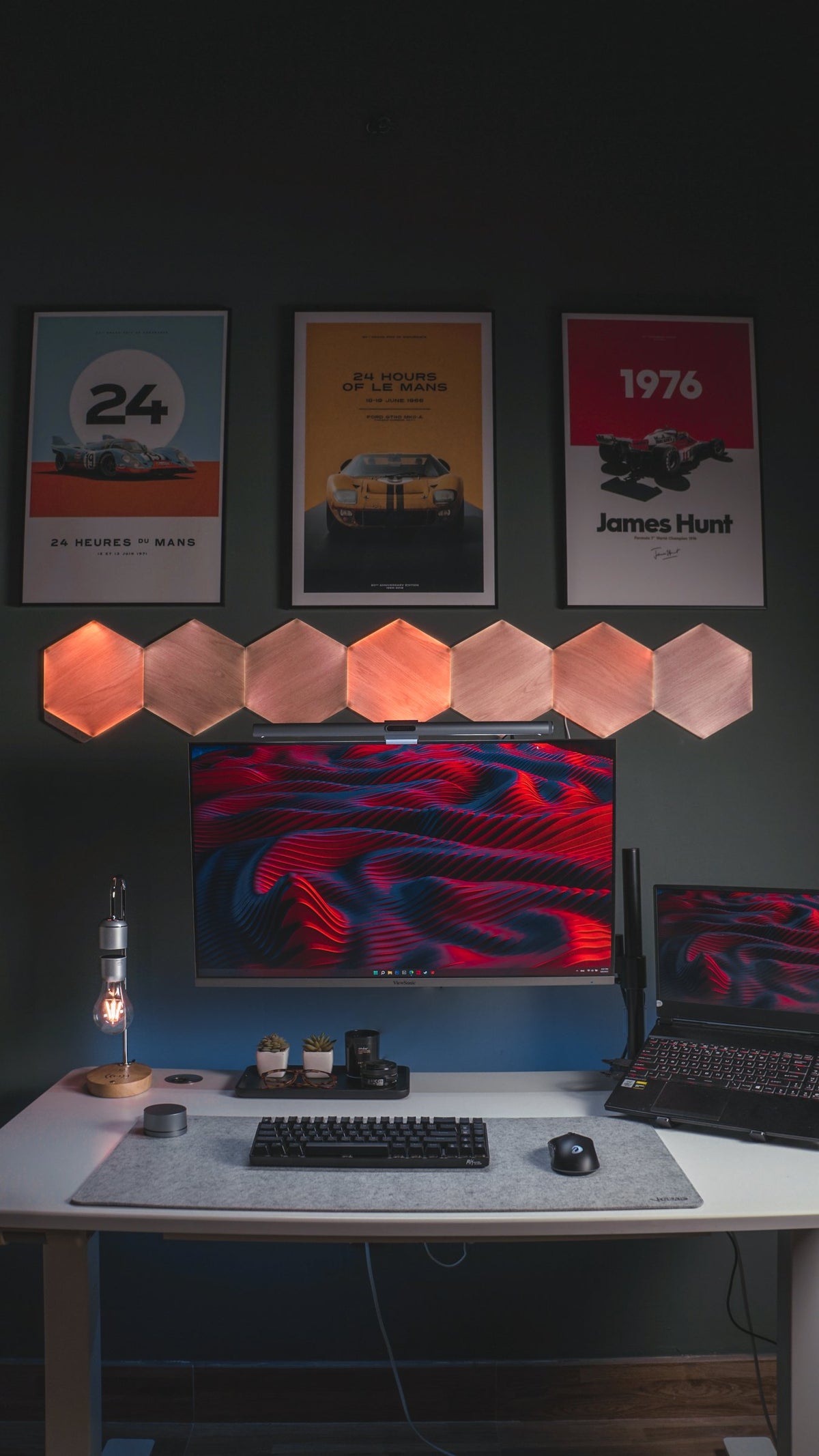 Vertical view of a white desk with red wave screens, racing posters and hexagon lights