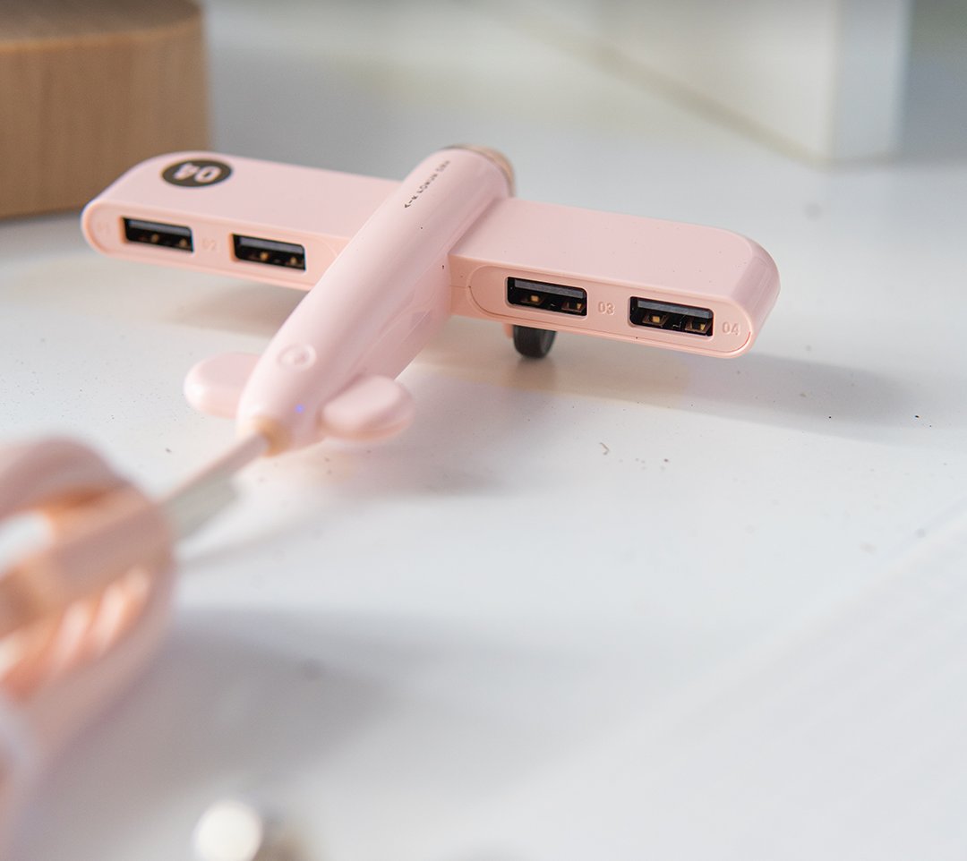 Pink airplane-shaped USB hub on a white desk