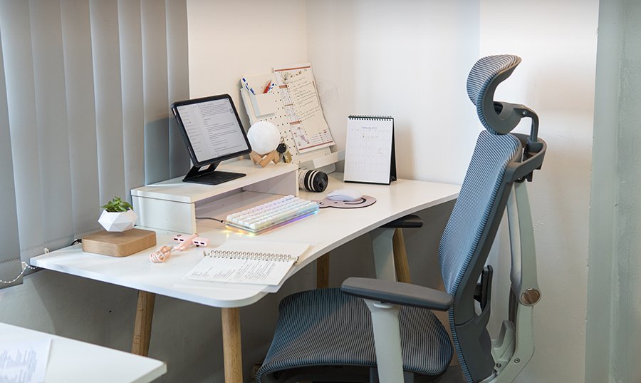 Soft white study desk with a tablet stand, pegboard, desk calendar and gray mesh chair