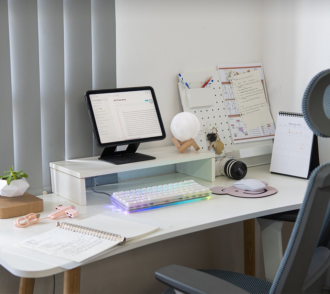 White desk with a tablet on a stand, moon lamp, pegboard notes and RGB keyboard
