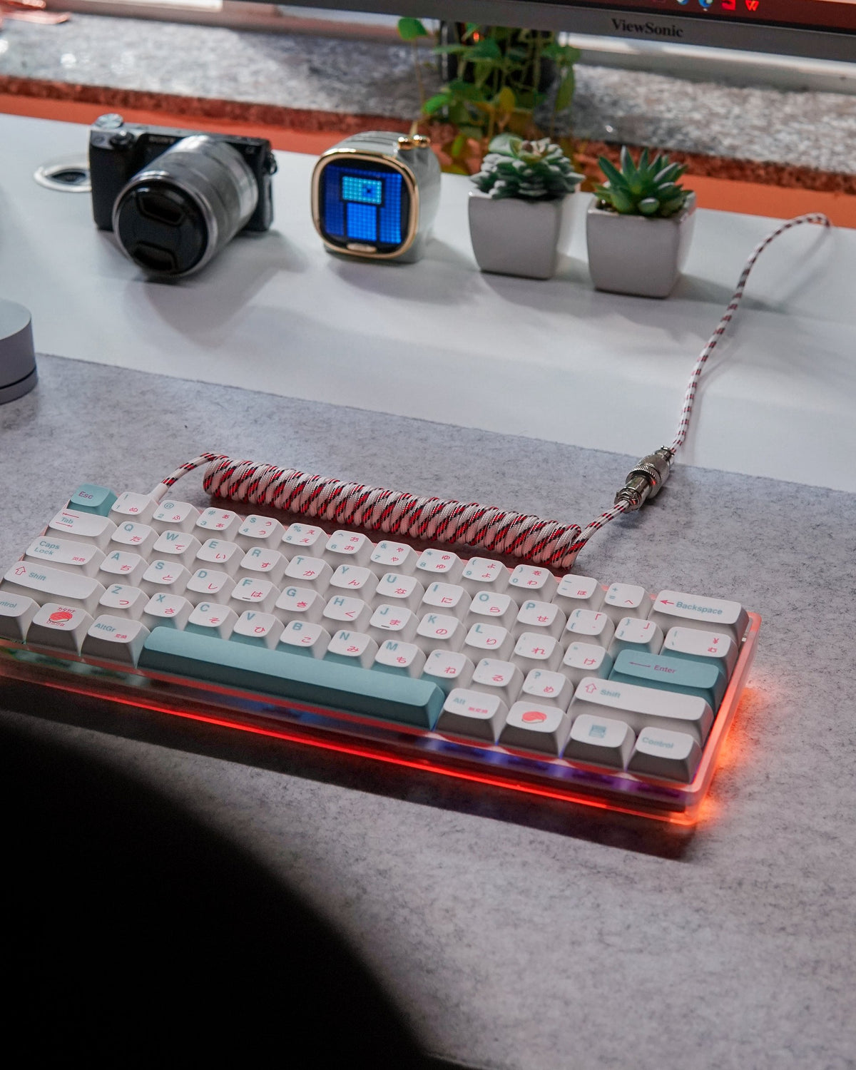 Pastel mechanical keyboard with a coiled cable, camera and small plants