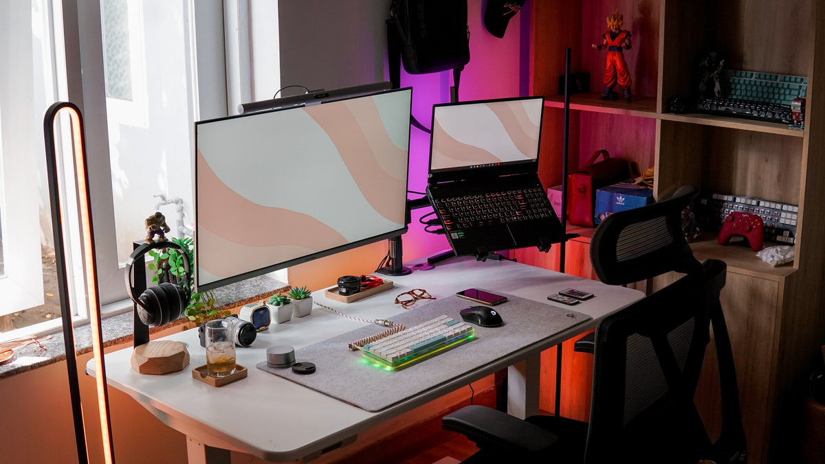 Sunny desk setup with a white monitor, laptop stand, plants and figure shelf