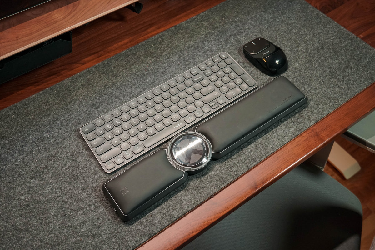 Top-down view of a slim keyboard with a wrist rest and mouse on a grey felt mat