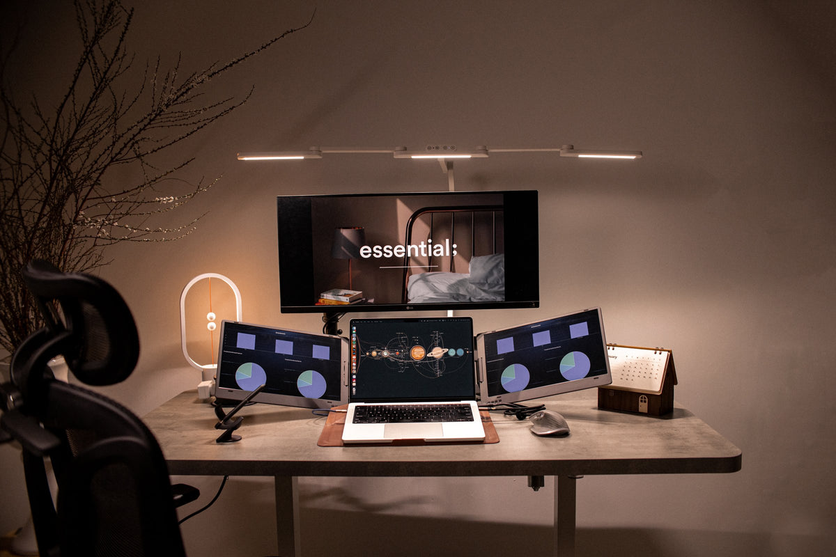Warm concrete-top desk with a center monitor, laptop and two portable side screens