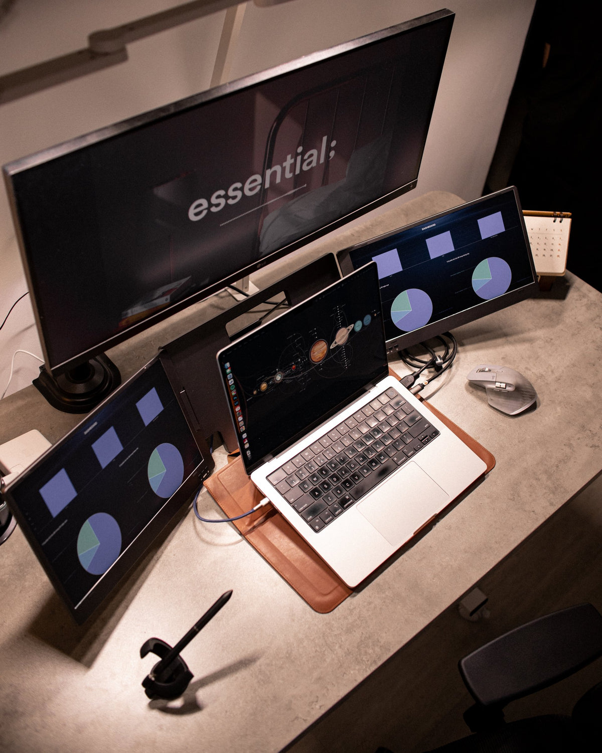 Laptop between two portable monitors on a concrete-top desk