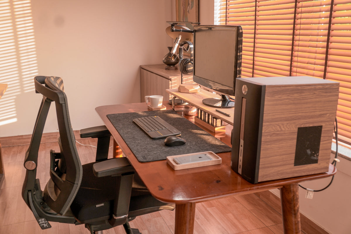 Warm-lit room with a wood desk, desktop tower and ergonomic chair