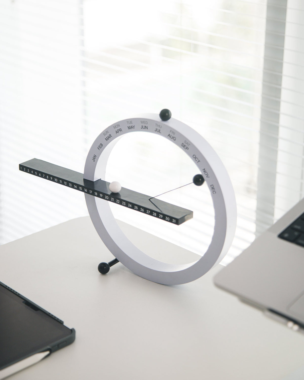 White orbit desk clock with a pendulum bar on a white desk