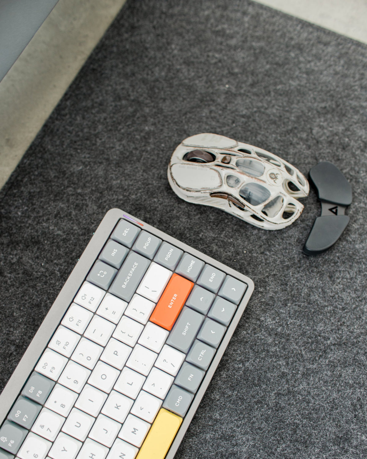 Close-up of a gray mechanical keyboard with orange and yellow accent keys and a white mouse