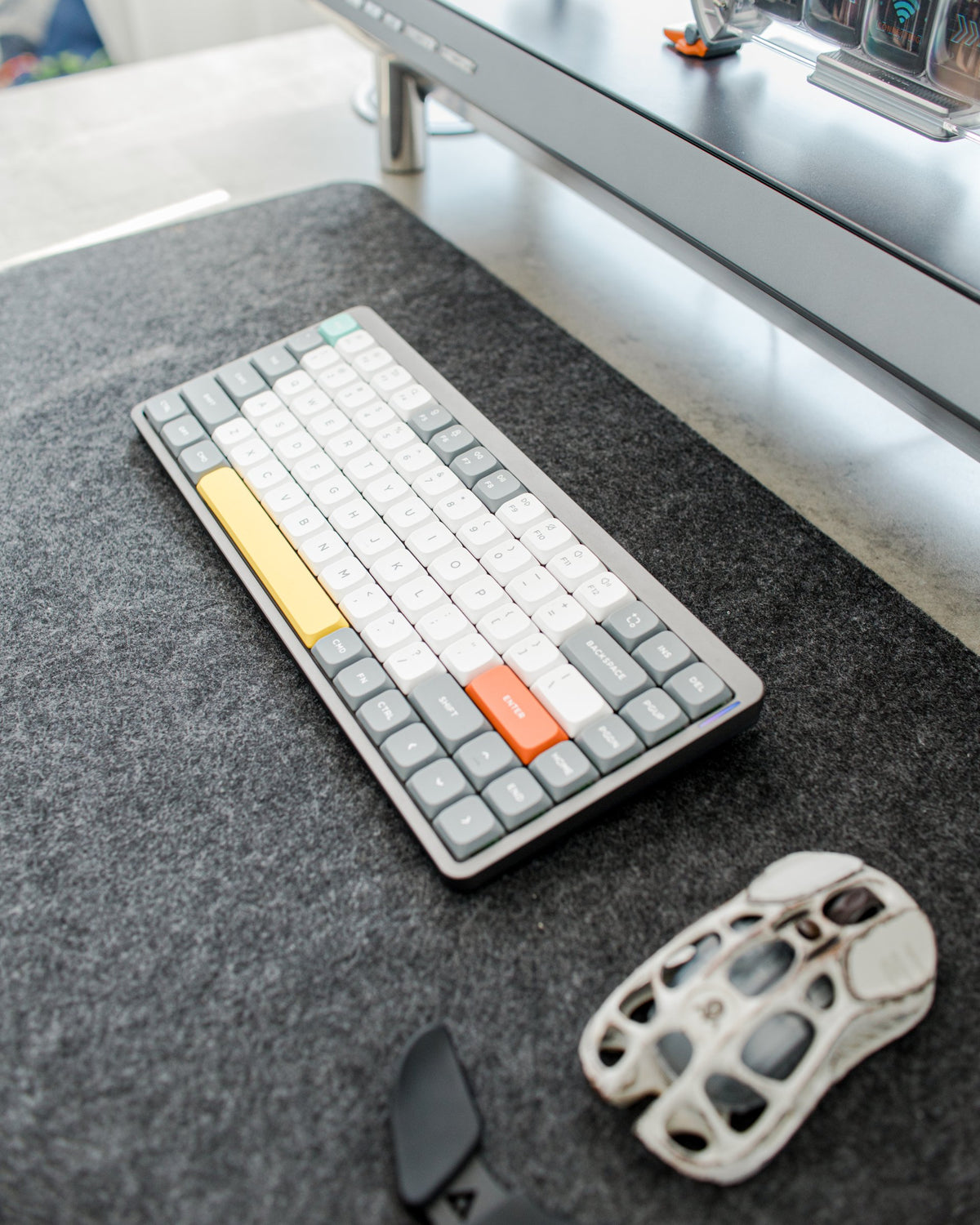Gray mechanical keyboard and skeleton mouse on a charcoal felt desk mat