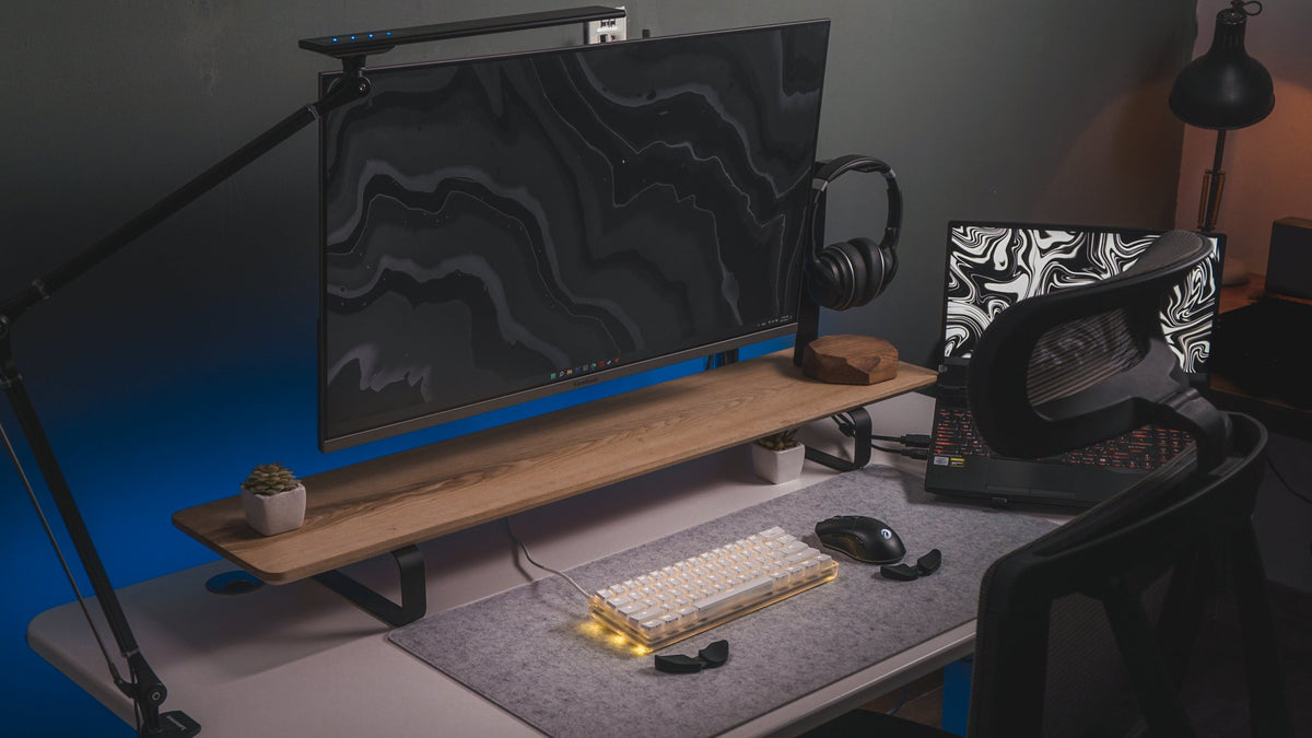 Dark desk setup with a wood monitor shelf, marble wallpaper, monitor light bar and a backlit keyboard