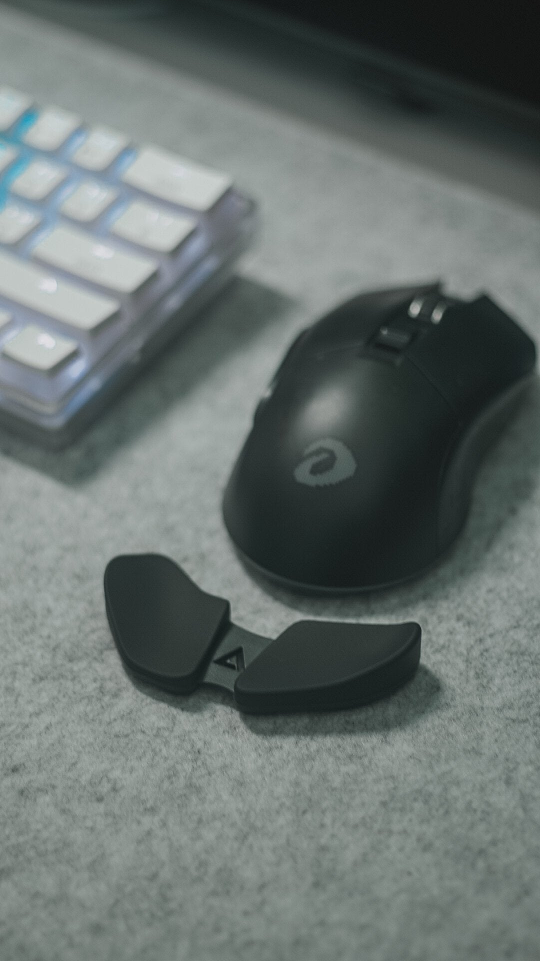 Black mouse and white keyboard on a gray felt desk mat
