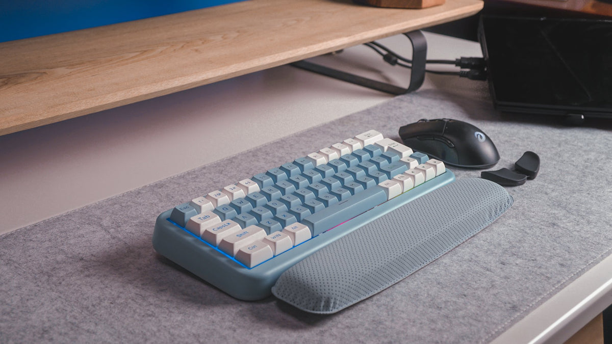 Blue and white mechanical keyboard with a wrist rest on a gray felt desk mat