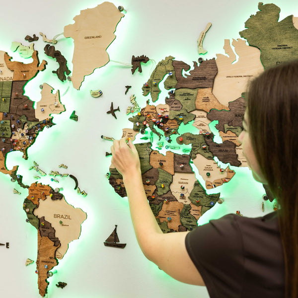 The wooden map with a green backlight while a person places a piece on the map