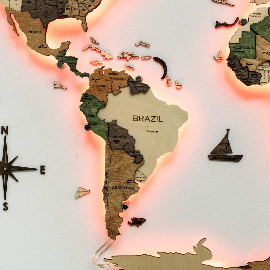 South America close up with a red backlight, a compass piece and a wooden sailboat