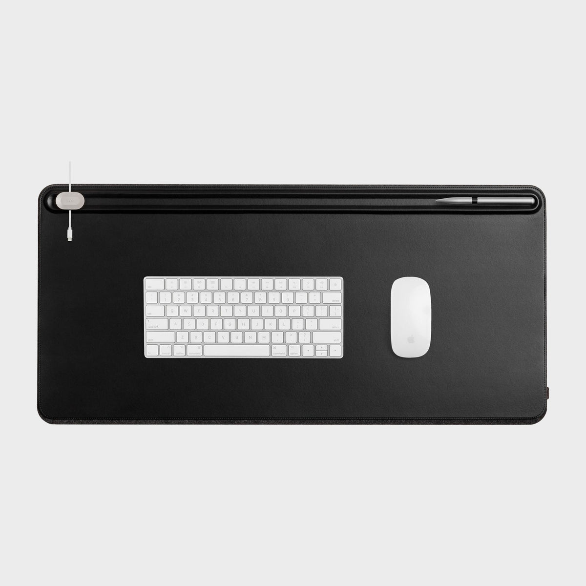 Black desk mat from above with a white keyboard and mouse on it