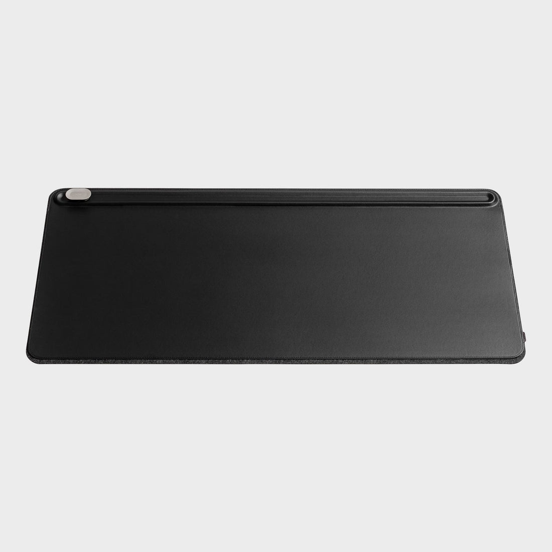 Black desk mat from the front with a groove along the top edge and a small clip