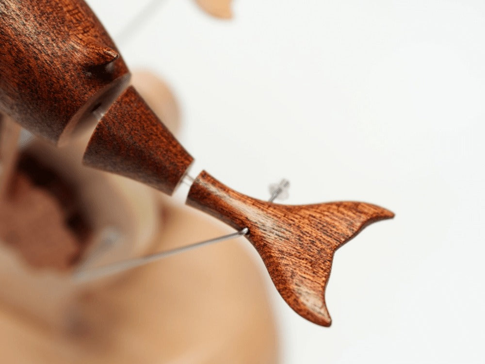 Close up of the dark dolphin tail and rear body with a thin wire running through.