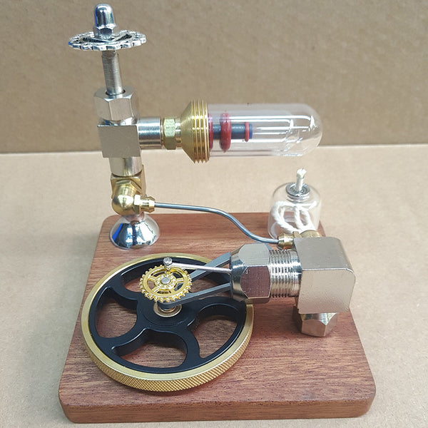 Stirling engine model on a wooden base with a black flywheel, glass cylinder and a small oil lamp, front three-quarter view