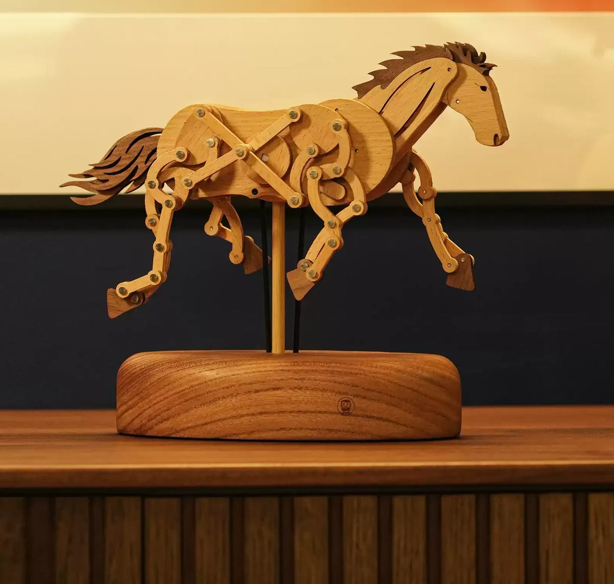 The wooden horse on a sideboard in warm light, its legs made of pinned wooden links.