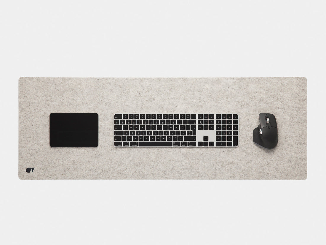Stone grey felt desk mat from above with a keyboard, trackpad and mouse