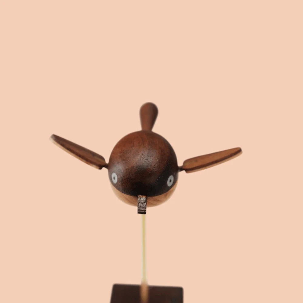 The bird head-on with both wings out, the round body in dark wood grain.