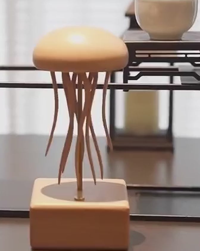 Wooden jellyfish automaton on its square base in front of a dark lattice shelf and a candle, tentacles in motion.