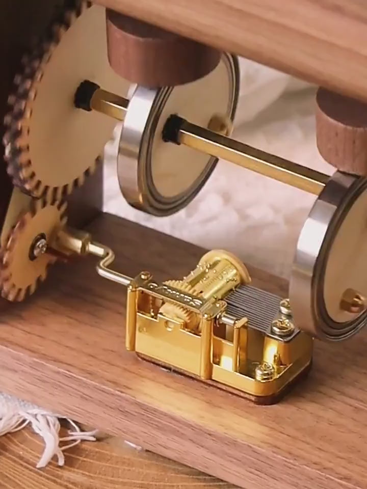 Close view of the blue-violet wooden whale rolling from head to tail on its brass rods as the crank turns.