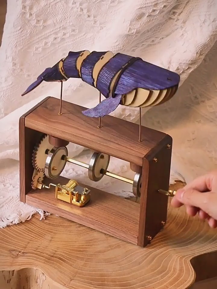Inside the frame: the gear wheel, three round cams on a brass shaft and the gold music box movement turning together.