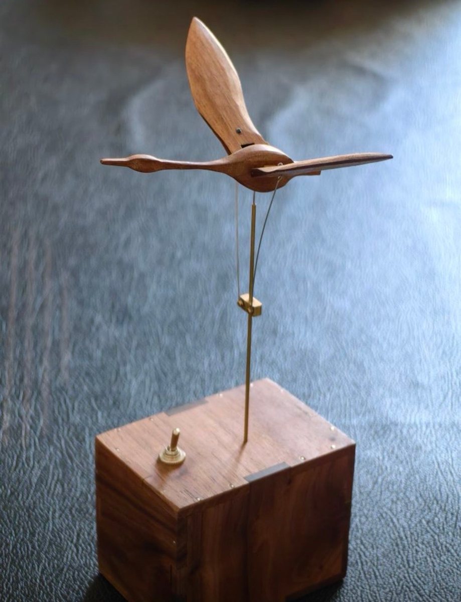 Swan above its walnut box on a dark table, wings spread wide.